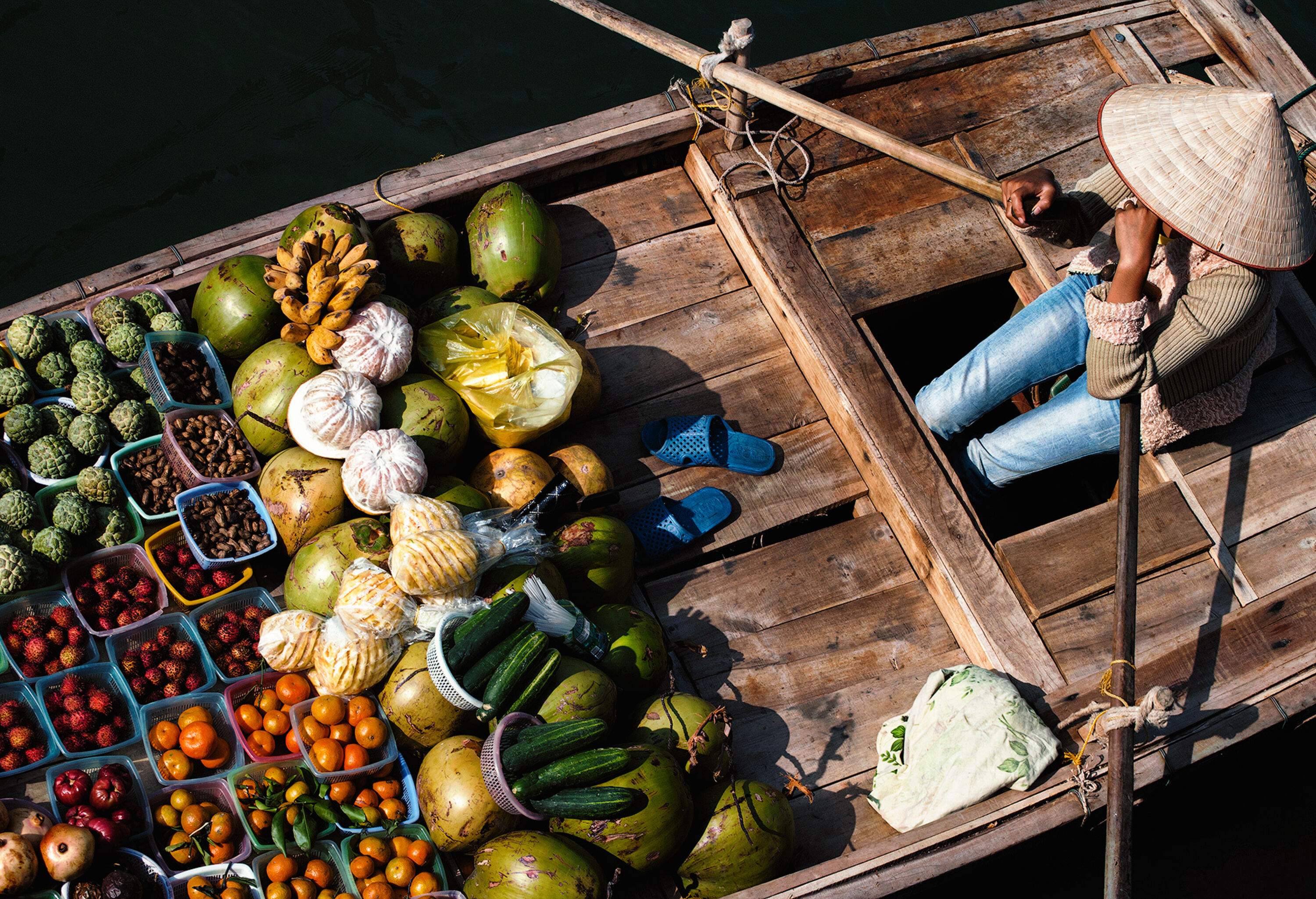 A lady fruit vendor sits on her wooden boat.