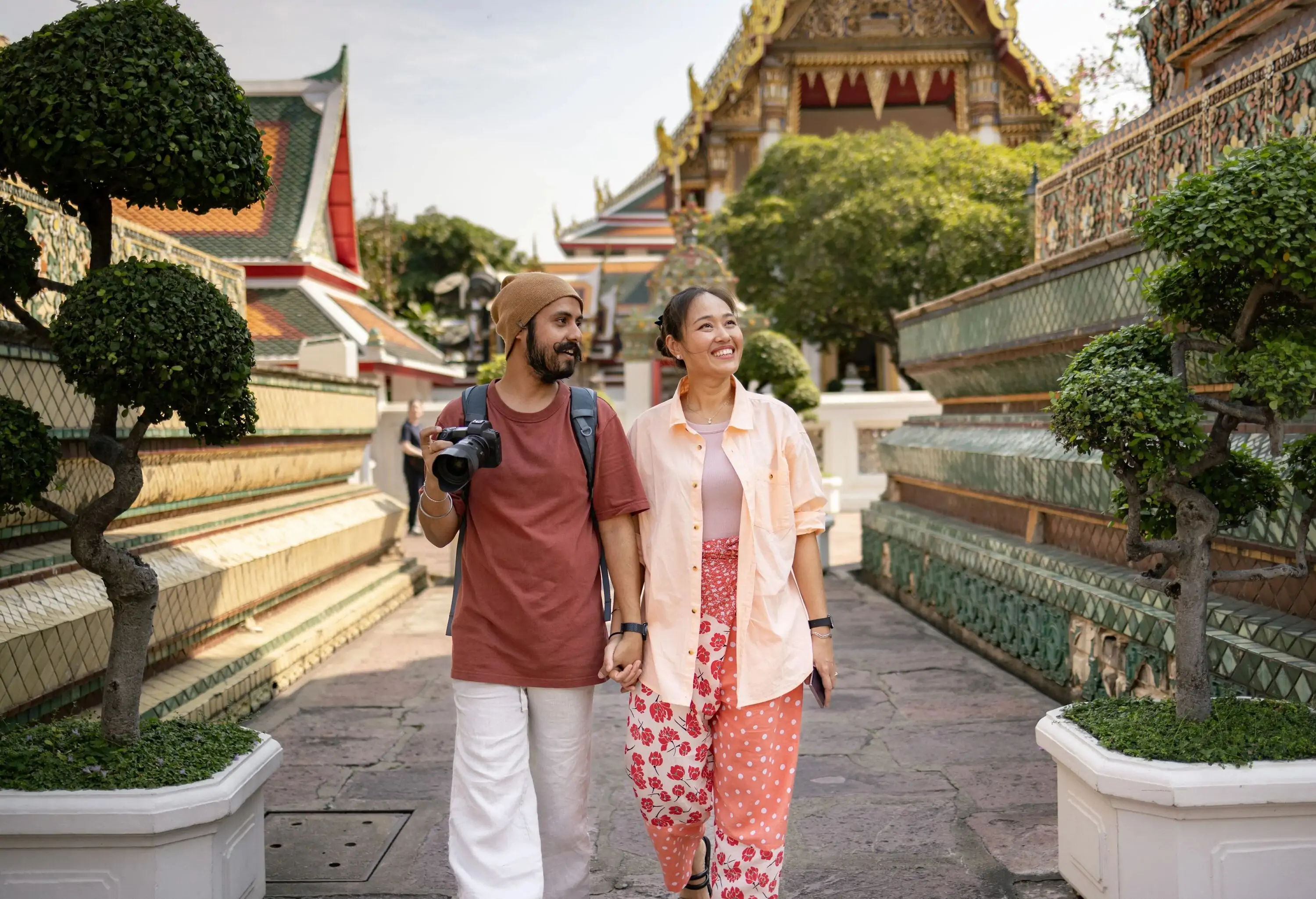 Happy couple of tourists holding hands while taking a walk through ancient place in Thailand.